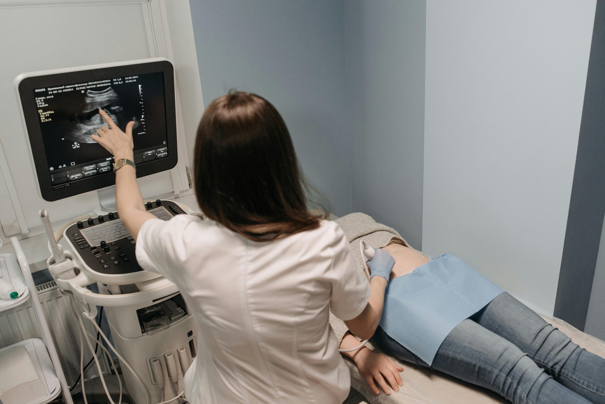 Female doctor conducting an ultrasound screening on a patient in a medical office.